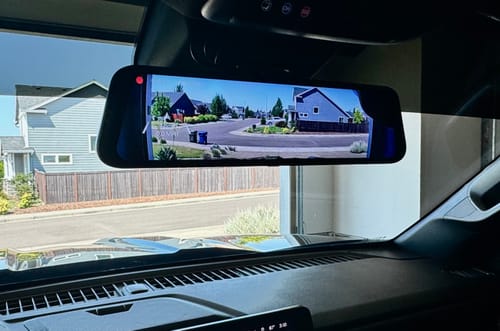 Reviewer's dash cam mirror installed in a car, displaying a clear video of a residential street.
