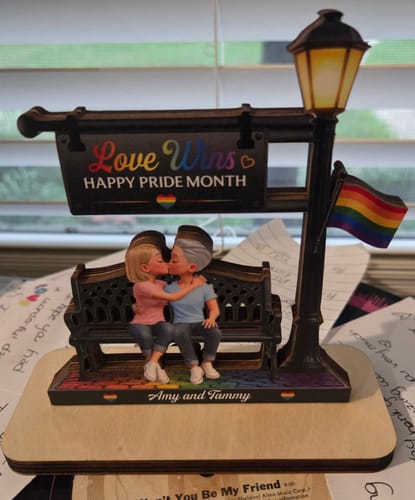 Customer's personalized wooden plaque showing two women kissing on a bench with 'Love Wins' and 'Amy and Tammy' printed on it.