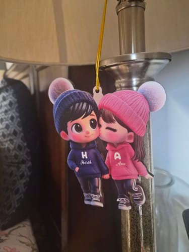 Customer's custom couple ornament showing a cartoon girl kissing a boy's cheek, with personalized names 'Harsh' and 'Anu'.