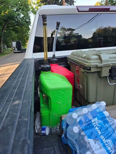 Customer's green and red 5 Gallon Jugs with spouts attached in the back of a truck.