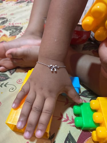 Customer's child wearing the silver bow bracelet on their wrist while playing.