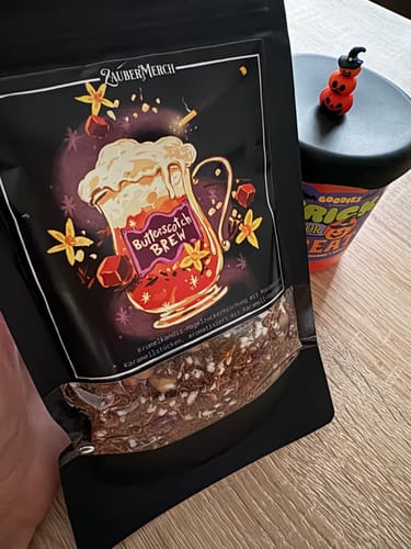 Rezensent hält die schwarze Packung des Butterscotch Brew Tees, der lose Tee ist durch ein Fenster sichtbar.