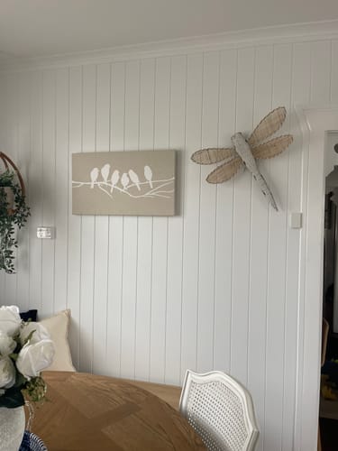 Reviewer's Lilly Dragonfly Wall Art mounted on a white paneled wall next to a small canvas in a dining nook.
