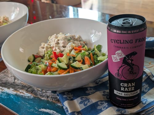 Customer's can of Cran Razz THC Seltzer served alongside a fresh salad in a white bowl.