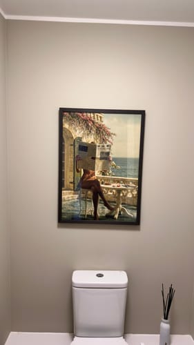 Customer's Black Oak Gallery Frame with an art print, hung on a wall in a bathroom.