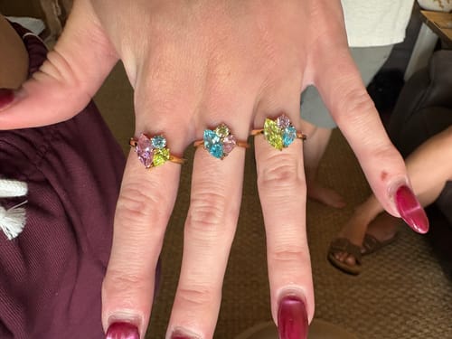 Customer's hand wearing three different Zia Birthstone Rings across their fingers to show the colorful stone combinations.