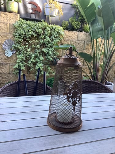 Customer's Stephanie Candle Lantern in an aged gold finish, shown on an outdoor patio table.
