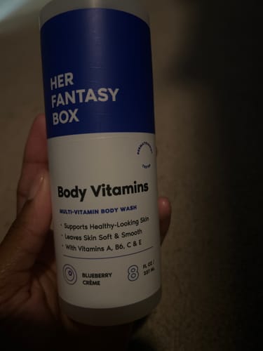 Customer's hand holding the white bottle of Body Vitamins Multi-Vitamin Body Wash.