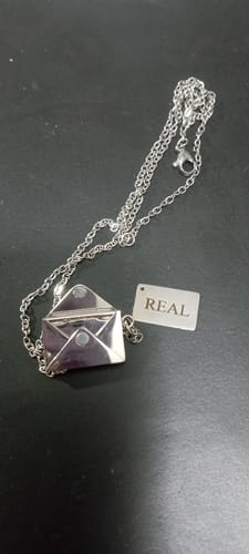 Cliente mostrando el Colgante Mensajero del Amor, un collar plateado con un colgante en forma de sobre.