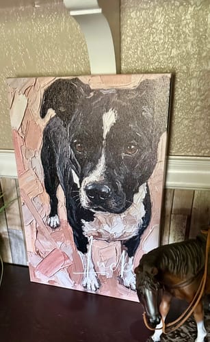 Customer's personalized painting-style canvas of a black and white dog, displayed on a dark wood shelf.