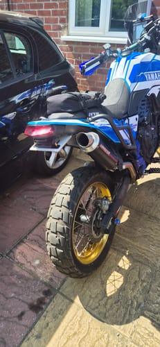 Customer's universal Plate Light illuminated on the rear of a blue and white motorcycle parked on a driveway.