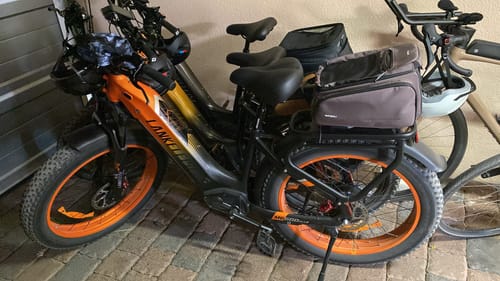 Reviewer's Lankeleisi MG600 Plus e-bike in black with orange rims and fat tires, parked on a brick patio.