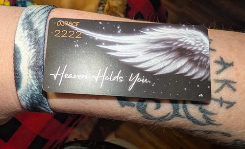 Close-up of a reviewer wearing the Heaven Holds You Bracelet, showing the front of the inspirational card on their arm.