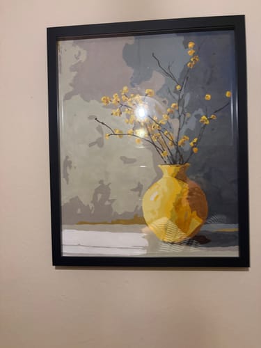 Kundenfoto des fertigen „Malen nach Zahlen – Goldene Vase“-Gemäldes, das in einem schwarzen Rahmen an einer Wand hängt.
