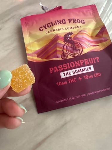 Reviewer holds a single sugar-coated Passionfruit Gummy in front of the product packaging.
