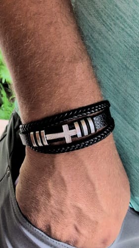 Customer wearing the Aegis Cross Bracelet on their wrist, showing the black braided leather and steel cross detail.