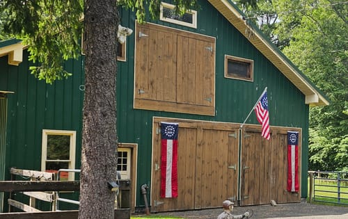 Customer's green barn displaying two Betsy Ross Pull Down Flags and a matching flag from the 250 Patriotic Decor Kit.