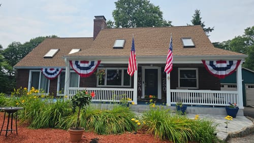 Customer's house decorated with two Americana pleated fans and American flags from the Patriotic Decor Kit on the front porch.