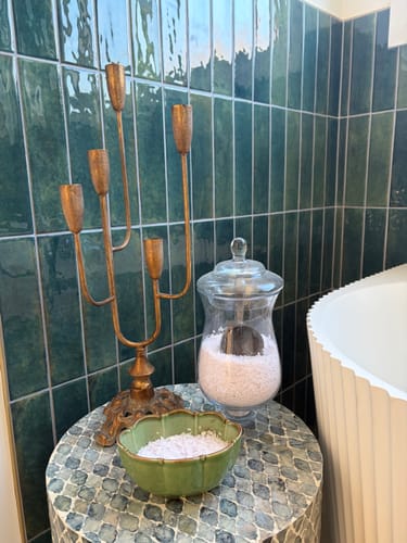 Customer's Lisette Candelabra with an antique gold finish on a tiled table in an ensuite bathroom.
