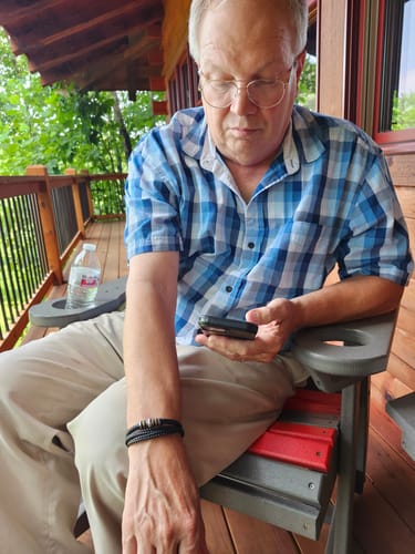 Customer wearing the black, braided bracelet while sitting on a porch chair.