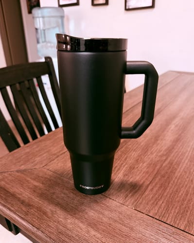 Customer's sleek black Thicc Buddy 40oz mug with its new lid resting on a wooden table.