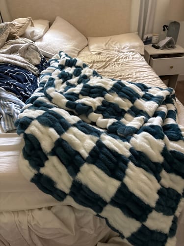 Customer's plush Hugs Check Blue Blanket with a navy and white checkerboard pattern on a bed.