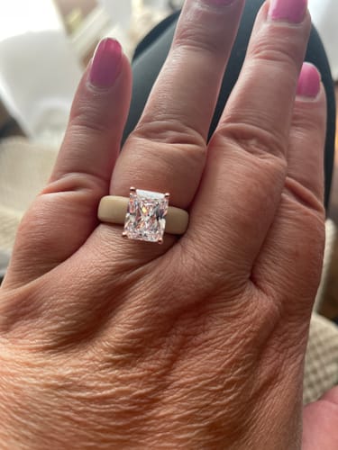 Customer's hand wearing the nude GlowStone silicone ring with a large, emerald-cut stone in a rose gold setting.