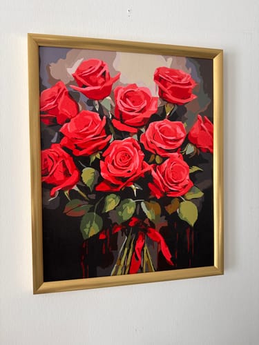 Ein Kunde zeigt das fertige "Malen nach Zahlen - Roter Blumenstrauß" Gemälde in einem goldenen Rahmen an einer Wand.