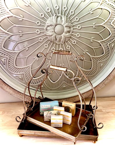 Customer's set of two Risette serving trays in antique gold, holding several small soaps in front of a decorative medallion.