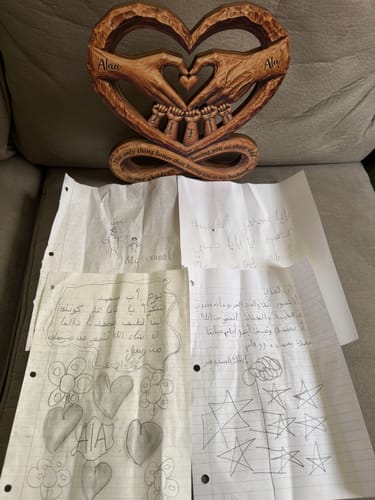 Customer's wooden heart-shaped sculpture with carved hands, shown with children's drawings.