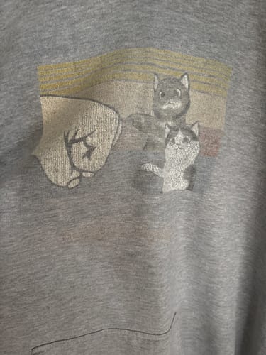 A reviewer's close-up of their well-worn grey sweatshirt with a faded 'Cat Fist Bump' graphic.