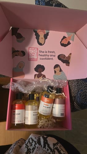 Customer unboxing the Body Splash Ultimate Bundle, showing several oils in a pink decorative box.