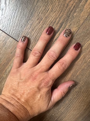 Kundenbewertung: Eine Hand mit einer Maniküre, die das glitzernde UV-Gel 'Red Sparkle' mit einem Leopardenmuster kombiniert.