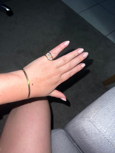 Customer's hand wearing the gold Pia Ring with a pear-cut stone on the pinky finger.