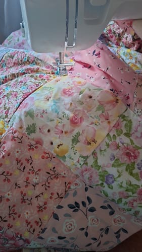 Reviewer sewing a patchwork quilt with various pink floral fabrics from the Print & Plain Fabric Bundle.