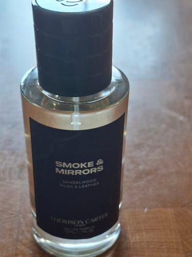 Customer's close-up photo of the Smoke & Mirrors Eau de Parfum bottle on a wooden surface.