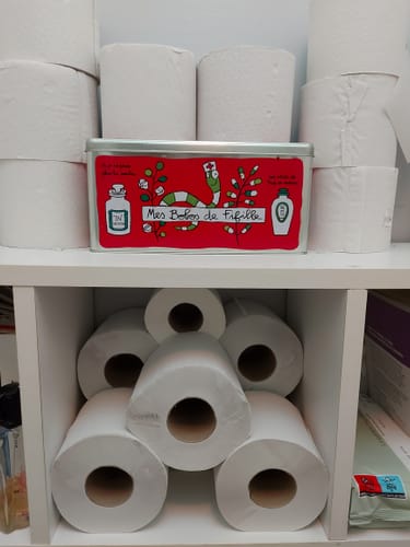 Photo d'un client montrant de nombreux rouleaux de papier toilette double épaisseur stockés sur une étagère blanche.