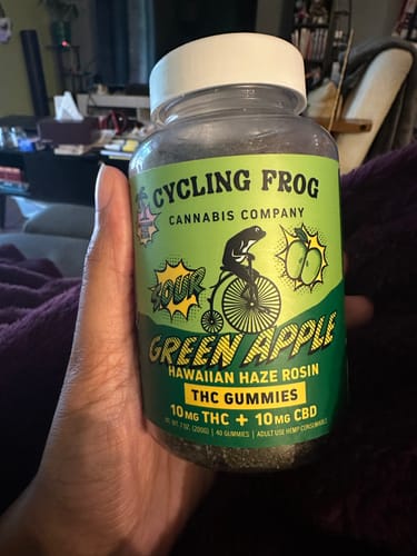 Customer's hand holding a clear jar of the Super Sour Green Apple Rosin Gummies.