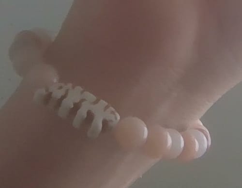 Close-up: Customer wearing The Prowl Bracelet, highlighting the white tiger charm among light-colored beads on a wrist.