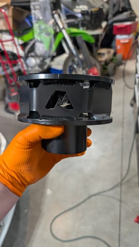 Customer's gloved hand holding a black steel 2.5" front spacer for the Ford Super Duty Leveling Kit, showing the quality welds.
