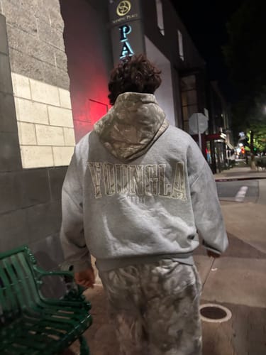 Reviewer from behind wearing the grey Tree Camo Hoodie, showing the relaxed, baggy fit while walking on a sidewalk at night.
