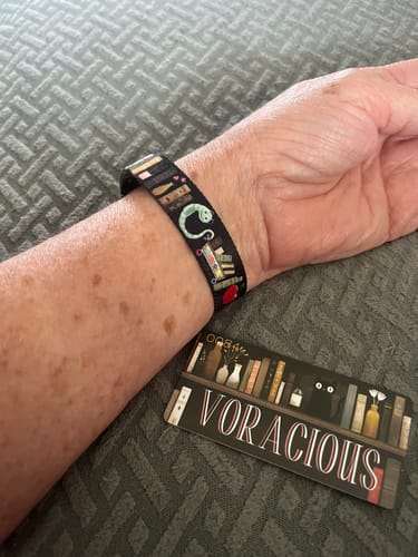 Customer wearing the black Book Challenge Voracious Bracelet, showing a green bookworm design.