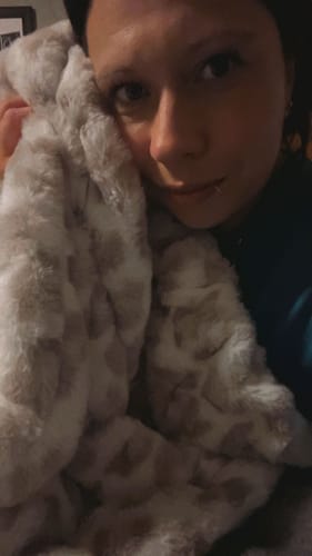 Close-up of a customer snuggling with their plush Hugs Snow Leopard Blanket.