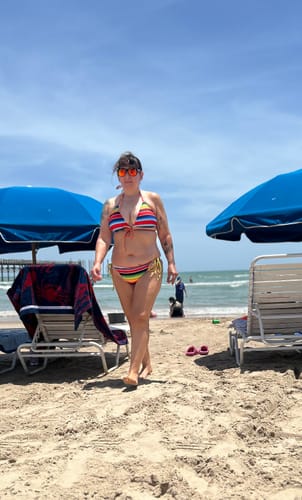 Customer walking on the beach wearing the colorful striped Mi Serape Sexy - String Bikini Top.