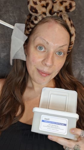 Reviewer holding Freshly Juiced Vitamin Skin Prep Pads with a pad used as a targeted mask on their face.