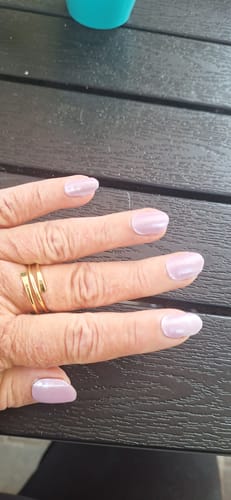 Nahaufnahme der Hand einer Kundin, die die schimmernden Lavender Chrome UV-Nagelfolien trägt.