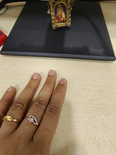 Reviewer's hand wearing the sparkling Rose Gold Blooming Flor Ring on their finger at a desk.