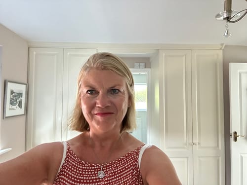 Reviewer smiling in a bedroom, pleased with the Lilium Blume Eau de Parfum.