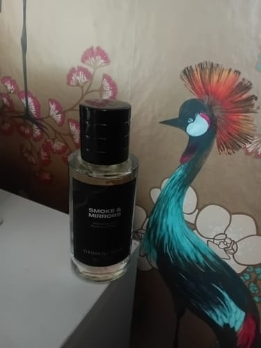 Customer's Smoke & Mirrors Eau de Parfum bottle with a black cap, resting on a white surface.