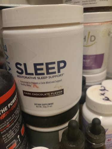 Customer's white tub of the Sleep supplement in Dark Chocolate flavor among other containers.